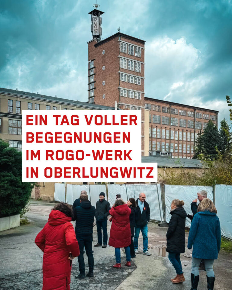 Das ROGO Werk in Oberlungwitz im Hintegrund, davor sieht man eine Ansammlung von Menschen. Der Himmel ist bewölkt.