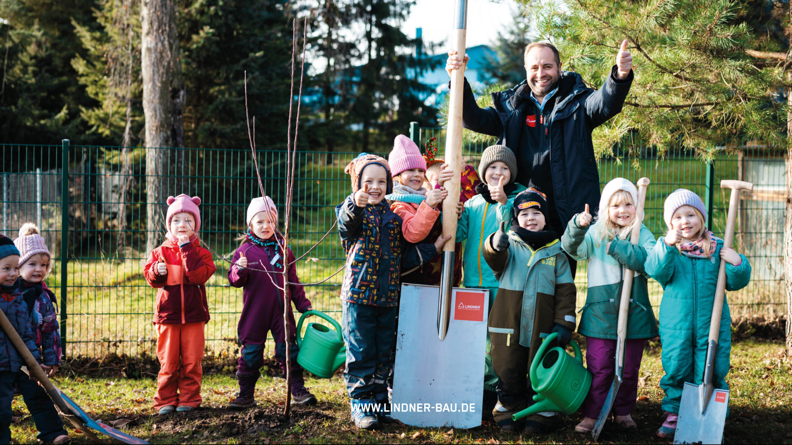 Zwei Bilder einer Baumpflanz-Aktion der Lindner Bau GmbH: Eine Gruppe von Kindern in bunter Winterkleidung pflanzt gemeinsam mit dem Geschäftsinhaber einen jungen Baum. Sie halten Schaufeln, Gießkannen und zeigen den Daumen nach oben. Im unteren Bildbereich ist die Website-URL www.lindner-bau.de eingeblendet.