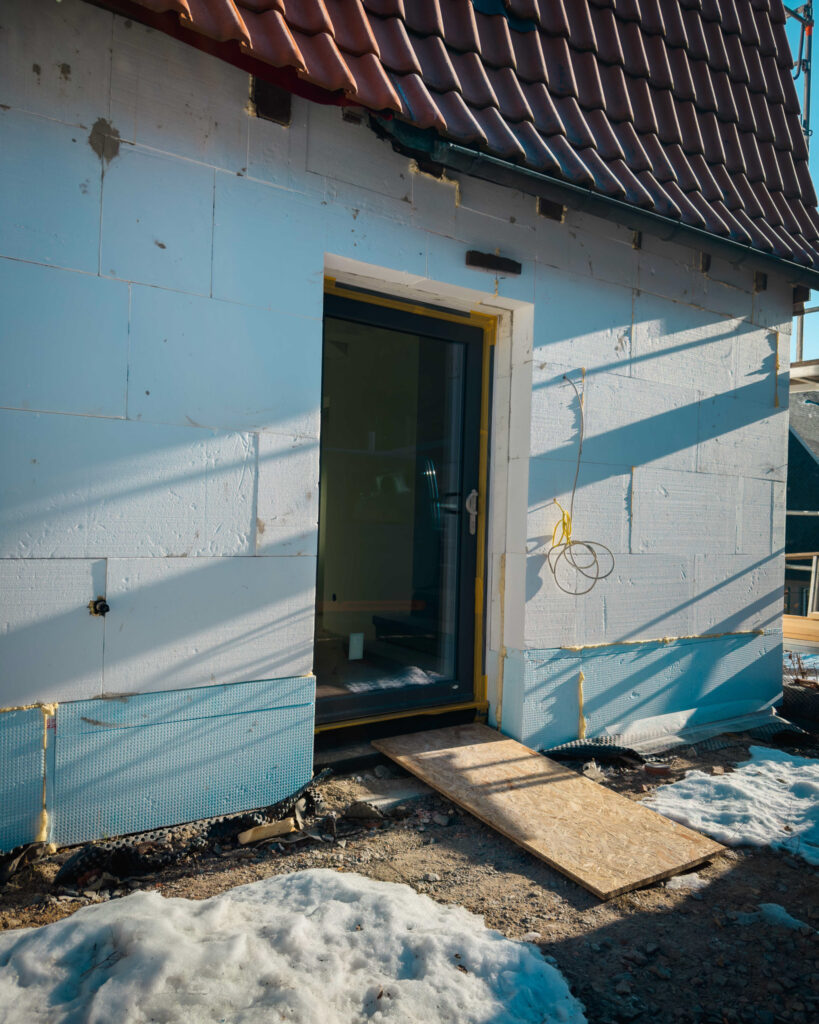 Detailansicht einer neu eingesetzten anthrazitfarbenen Terrassentür und weißer WDVS-Fassadendämmung im Außenbereich.