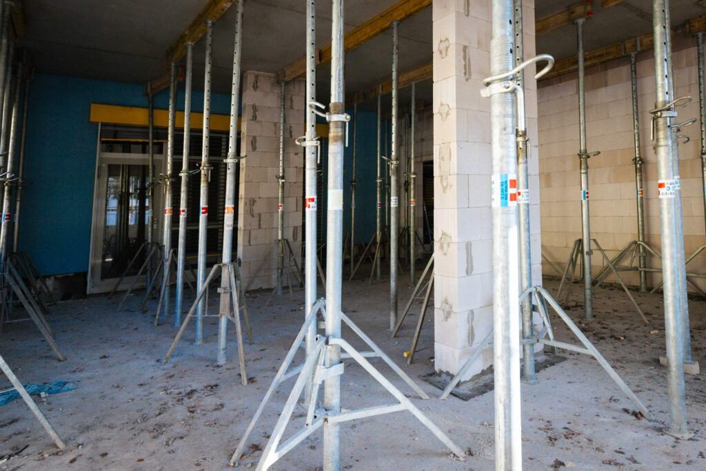 Innenansicht eines Rohbaus mit zahlreichen Baustützen zur Deckenschalung während der Sanierungsphase eines Klinikgebäudes.