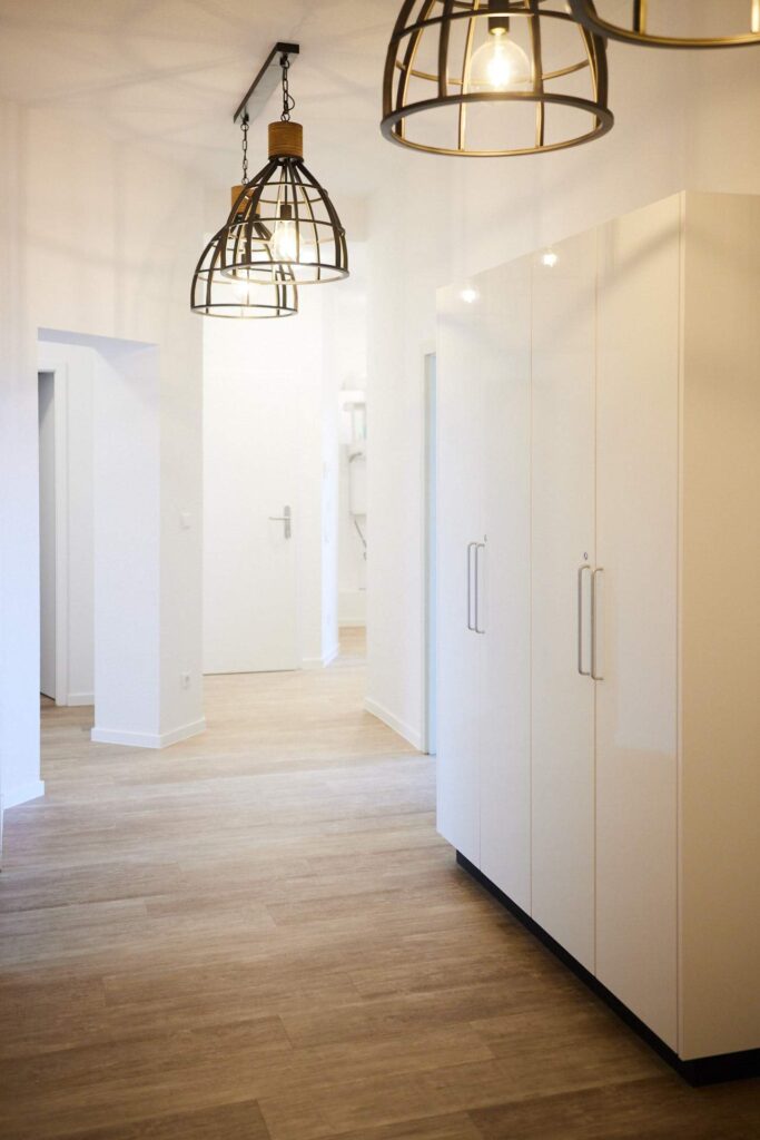 Modernisierter Praxisflur in Chemnitz: Hochwertige Bodenbelagsarbeiten und maßgefertigte weiße Einbauschränke für maximale Ordnung und Struktur.