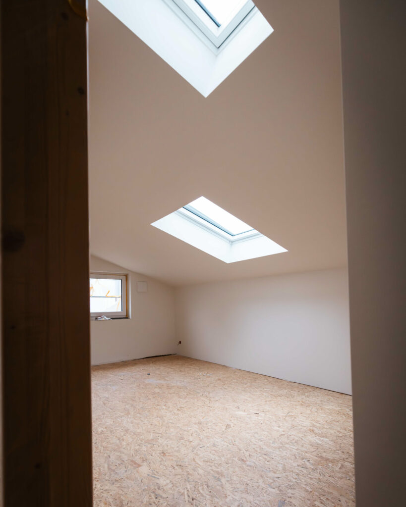 Dachgeschossausbau mit zwei modernen Dachflächenfenstern und OSB-Platten als Unterboden.