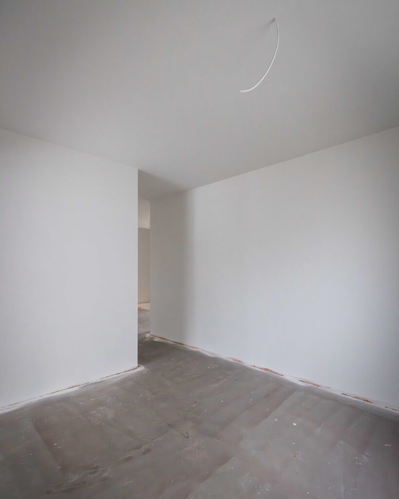 Innenraum-Ansicht mit weiß gestrichenen Wänden und Vorbereitung für die Elektroinstallation an der Decke.