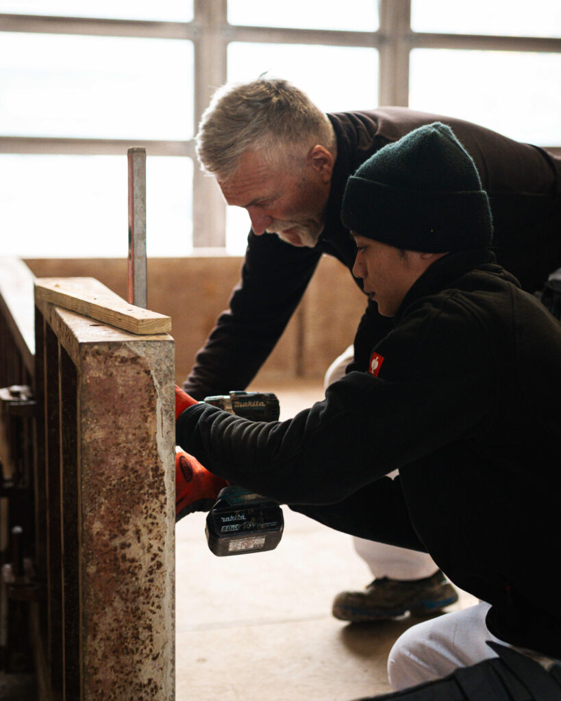 Zwei Handwerker bei der präzisen Montage einer Schalungswand mit einem Akkuschrauber.