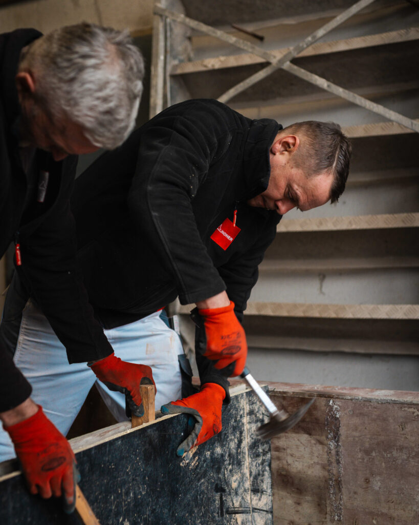 Bauarbeiter bei der Montage von Schalungsholz unter Einsatz eines Hammers.