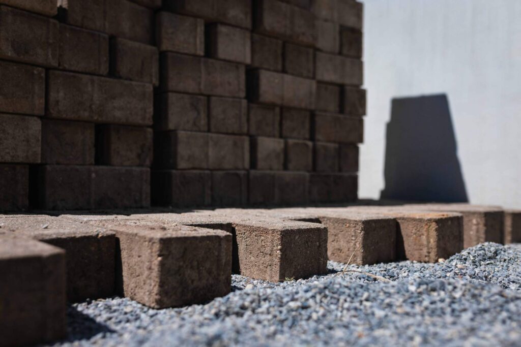 Detailansicht von gelagerten Pflastersteinen auf Splittbett für die Bodenversiegelung im Außenbereich.