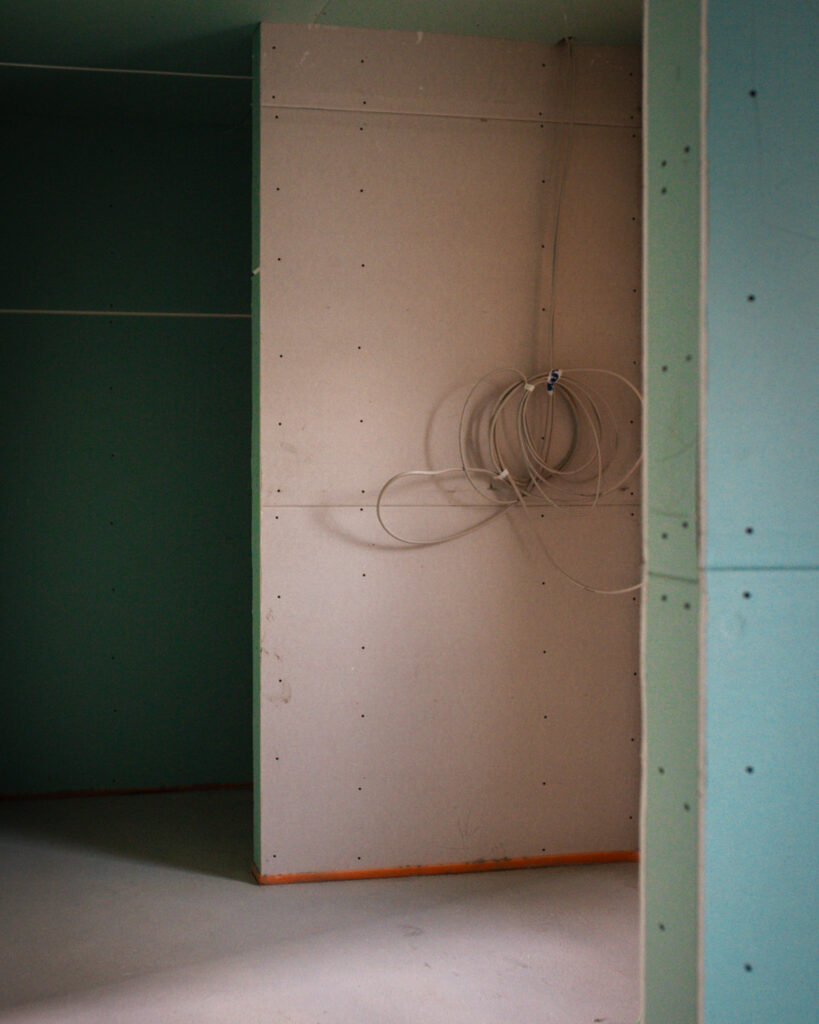 Detailansicht einer Trockenbauwand mit vorbereiteter Elektroinstallation und grünen Gipskartonplatten für Feuchträume.