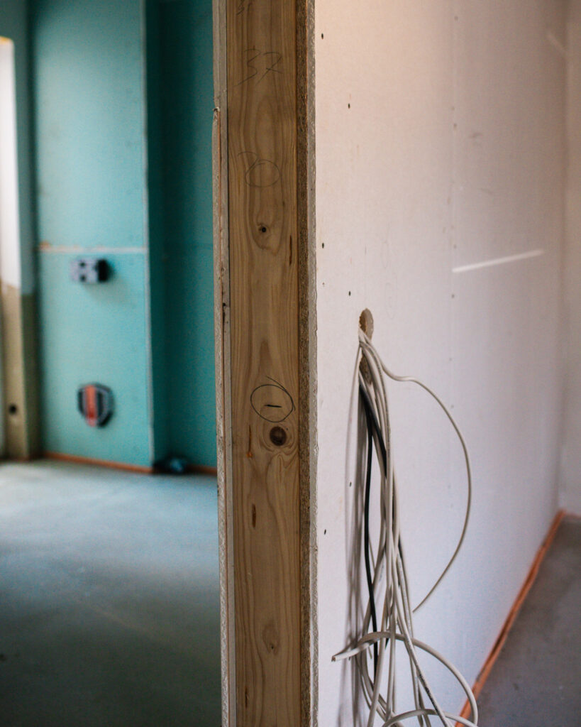 Blick auf eine Holzständerwand im Trockenbau mit heraushängenden Kabelbündeln für die spätere Elektroinstallation.