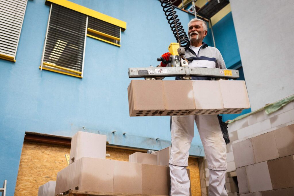 Ergonomisches Arbeiten mit moderner Technik: Lindner Bau nutzt Versetzgeräte für schwere Kalksandsteine im Klinik-Rohbau.