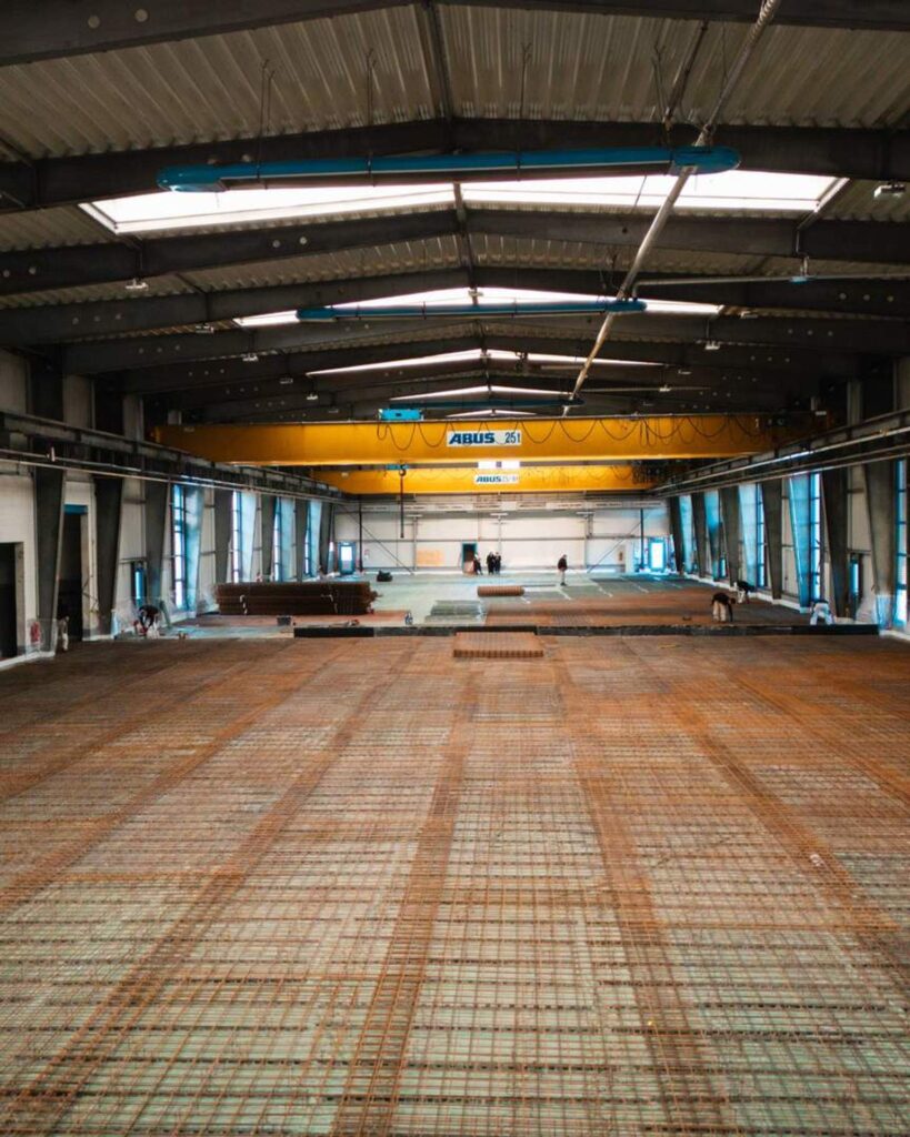 Innenansicht der Baustelle in Chemnitz: Großflächig verlegte Stahlbewehrung auf Folie zur Vorbereitung der neuen Industrie-Bodenplatte.