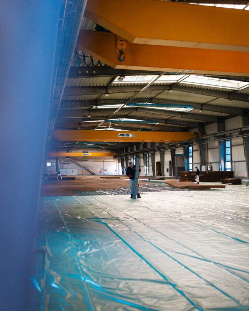 Blick durch die Baustelle von Lindner Bau in Chemnitz; im Hintergrund der gelbe Hallenkran und die weitläufigen Vorbereitungen für die Betonarbeiten.