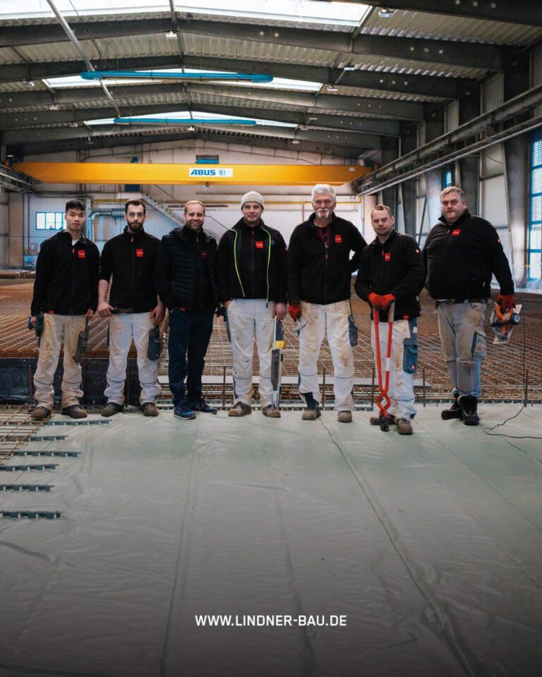 Das Baustellen-Team von Lindner Bau vor der beeindruckenden Kulisse der vorbereiteten Bodenplatte im Autohaus Fugel, Chemnitz.