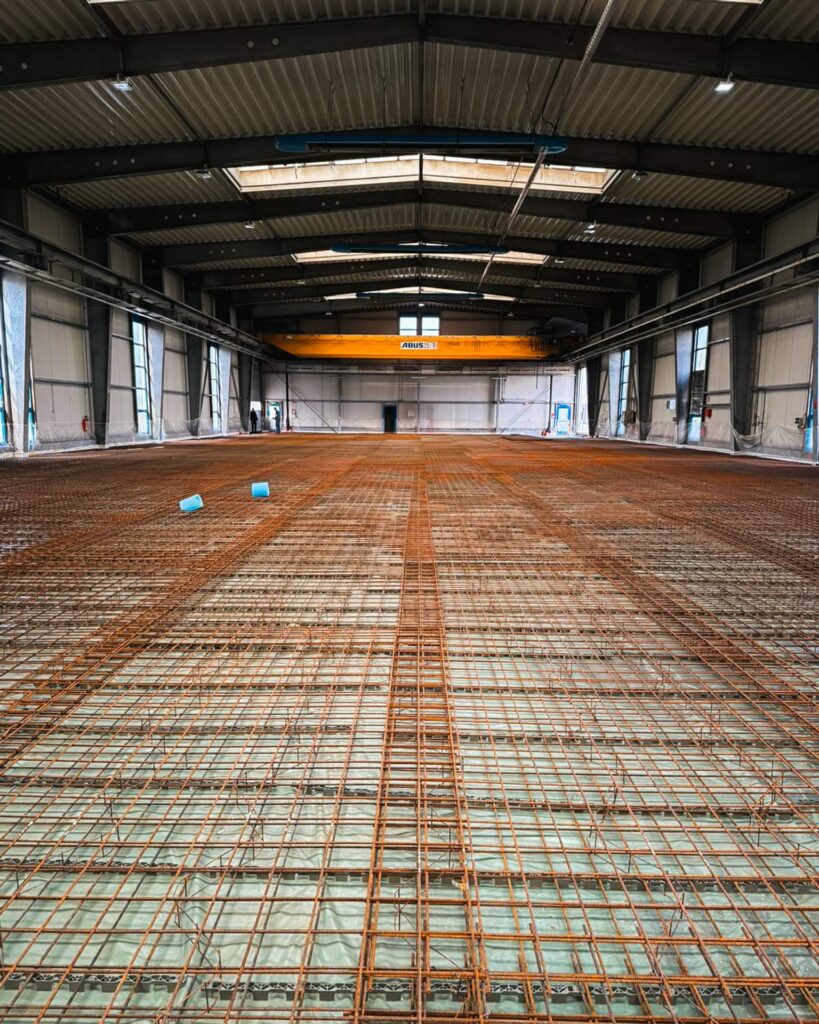 Vorbereitung einer Industriehalle für den Betonboden: Großflächige Stahlbewehrung auf einer PE-Folie verlegt vor dem Gießen.
