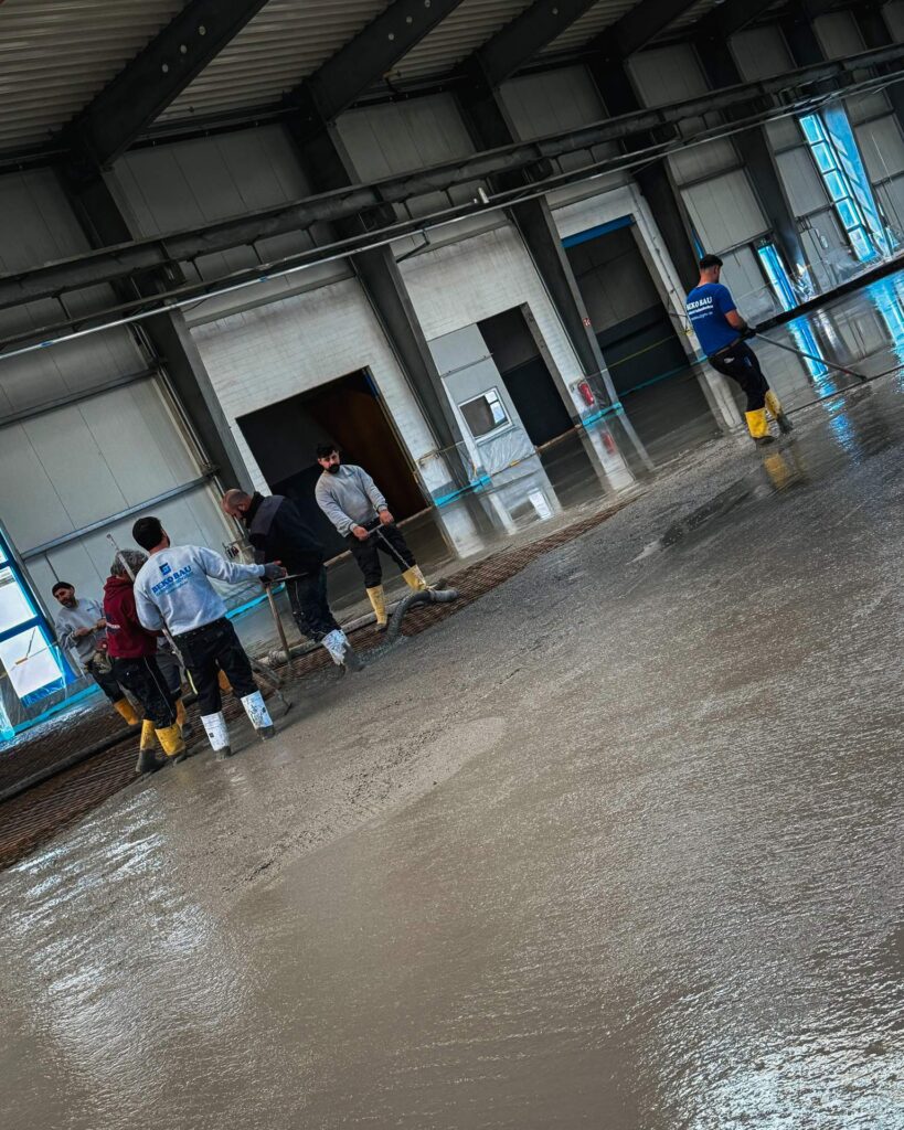 Präzises Glätten der Betonoberfläche in einer Industriehalle durch Facharbeiter der Firma Beko Bau.