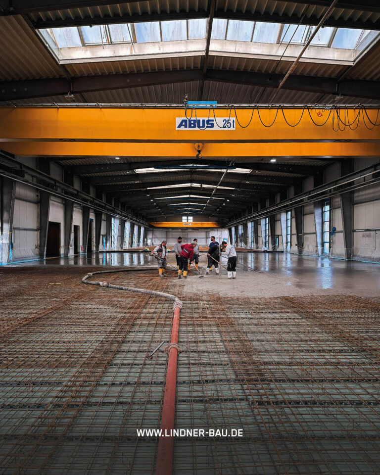 Großprojekt Industriebau: Lindner Bau Team bei der Installation eines hochbelastbaren Betonbodens in einer weitläufigen Logistik-Halle.