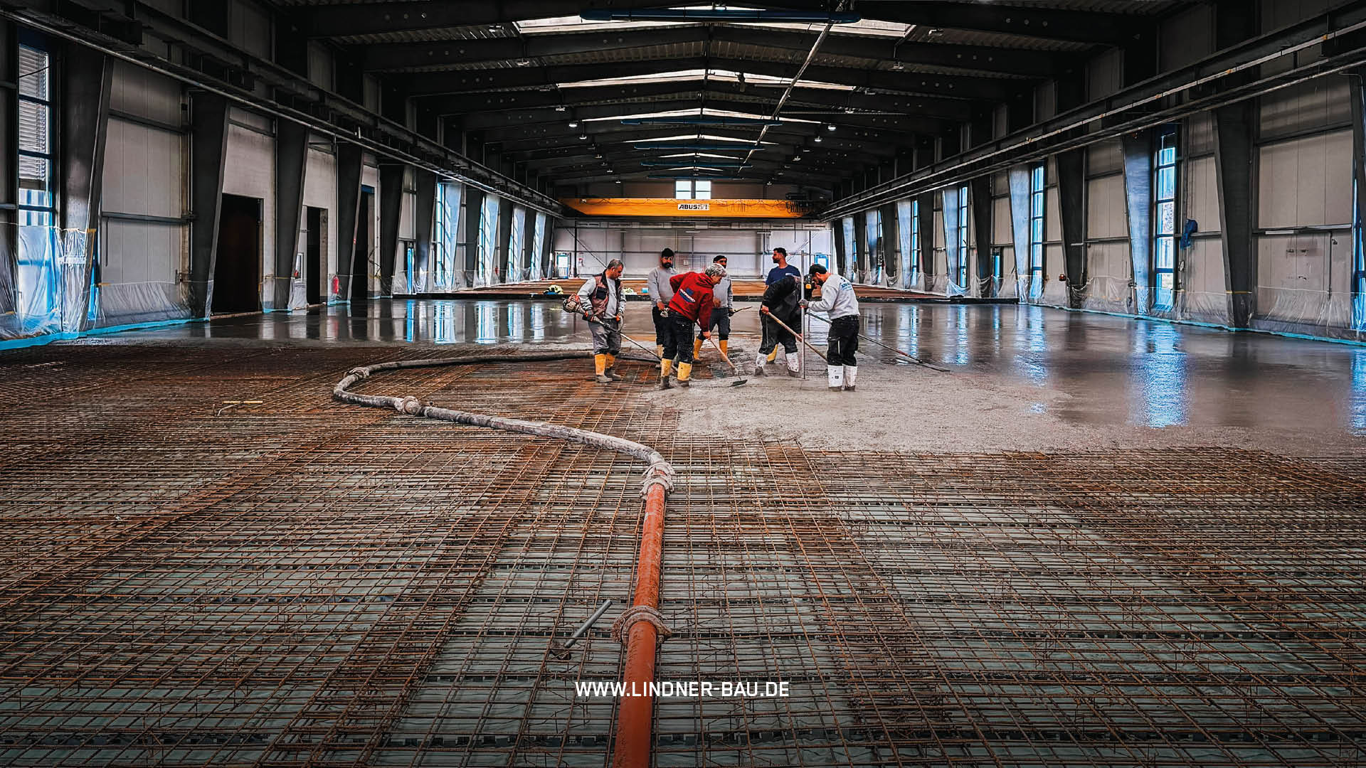 Großprojekt Industriebau: Lindner Bau Team bei der Installation eines hochbelastbaren Betonbodens in einer weitläufigen Logistik-Halle.