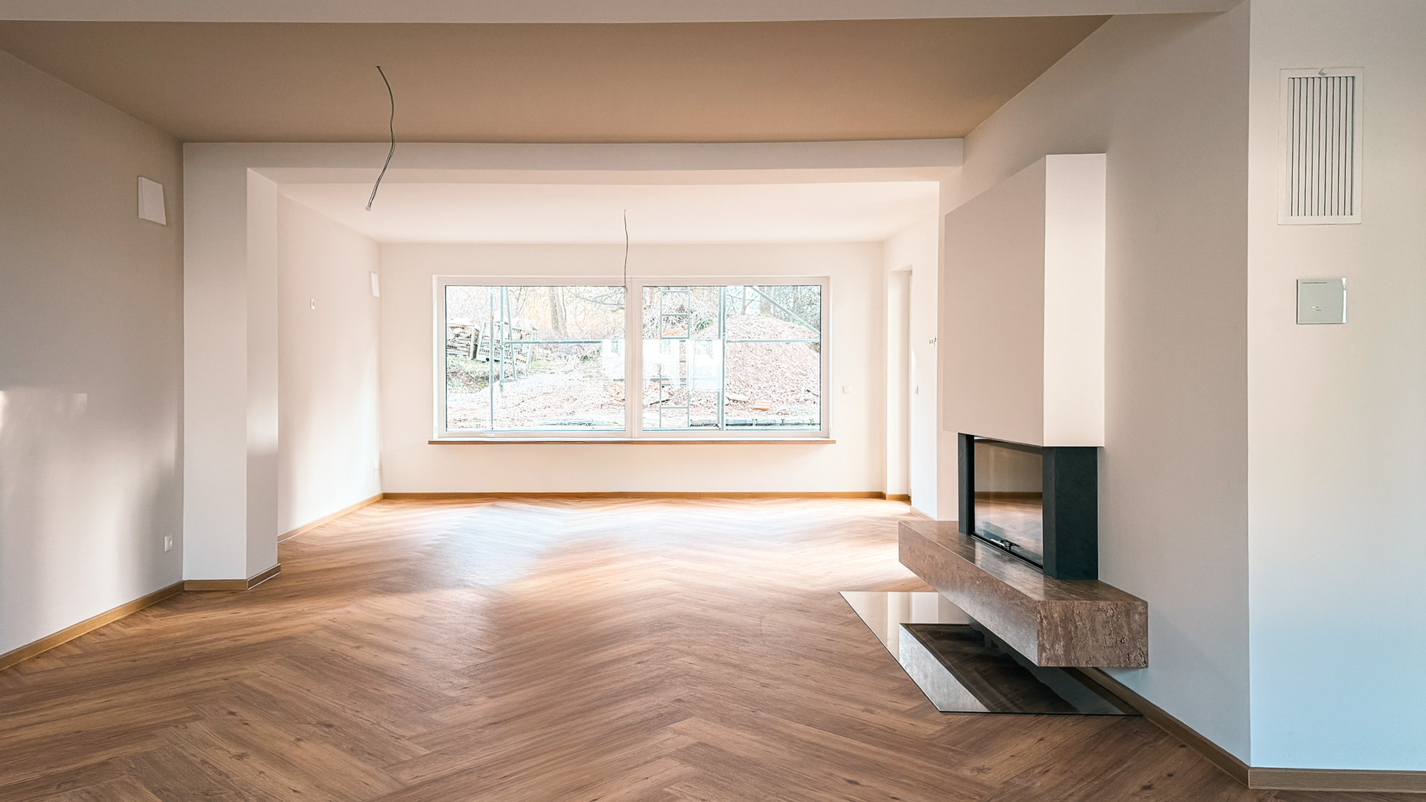 Modernes, helles Wohnzimmer im Neubau mit hochwertigem Echtholz-Parkett im Fischgrät-Muster und minimalistischem Kamin.