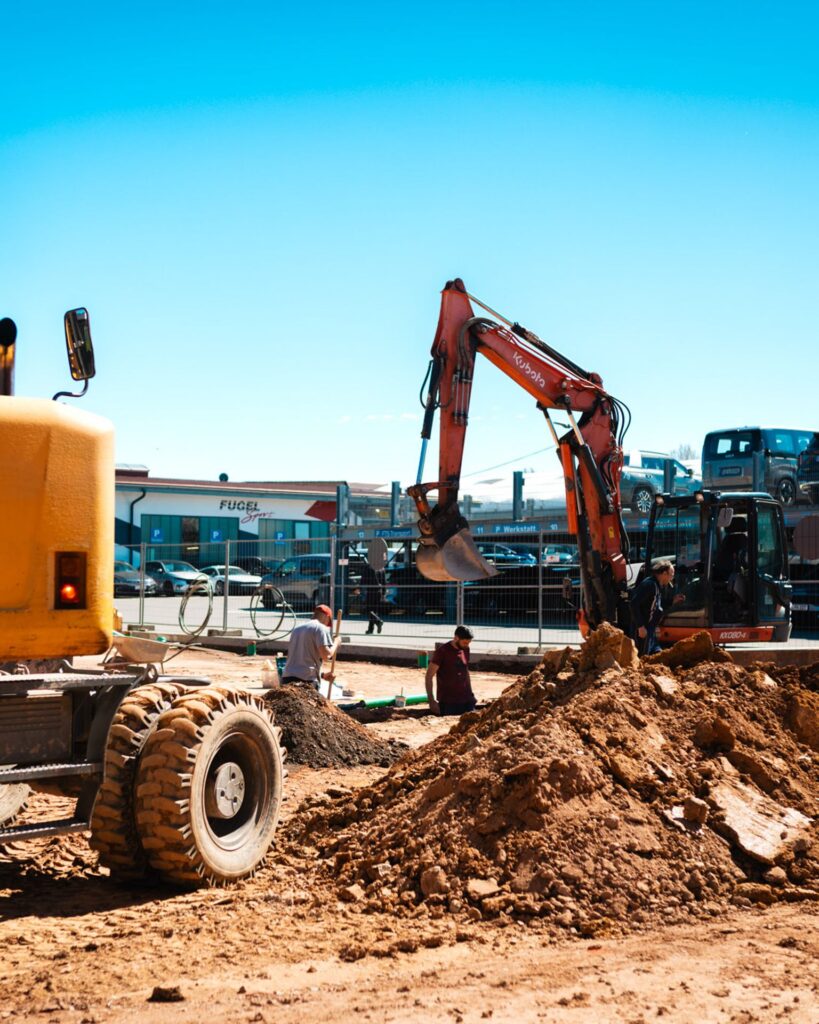 Erdbauarbeiten auf der Fugel-Autohaus-Baustelle mit Baggern und Erdhaufen.