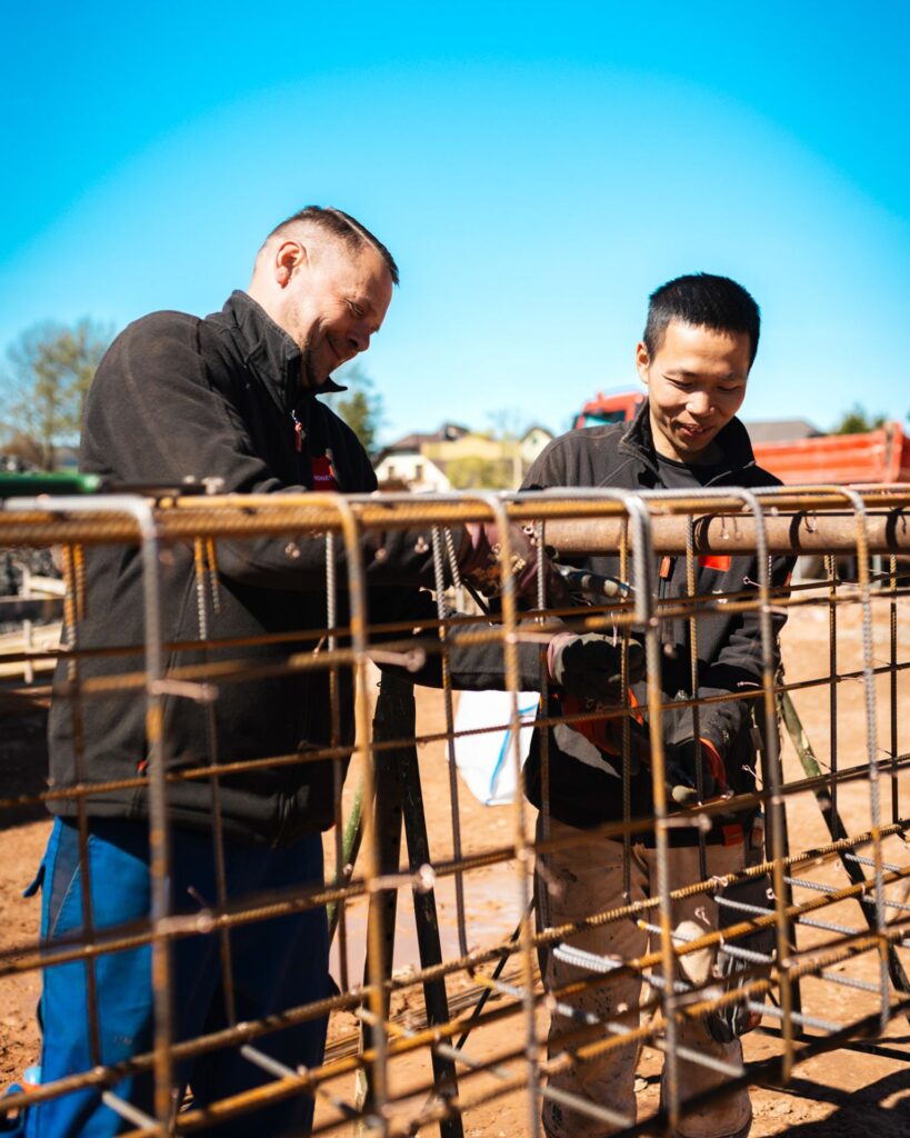 wei Bauarbeiter binden Betonstahl auf der Baustelle für das neue Fugel-Autohaus.