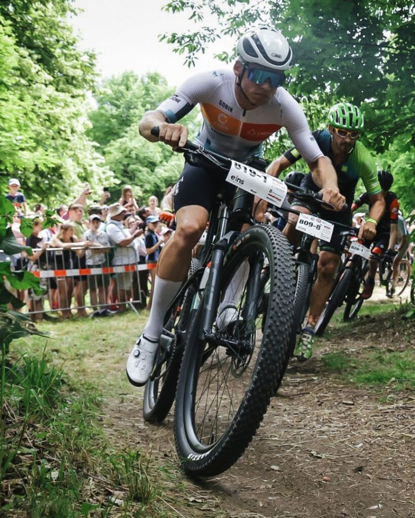 MTB-Fahrer vom Team Fritzsche führt das Fahrerfeld auf einer anspruchsvollen Waldstrecke vor Zuschauern an