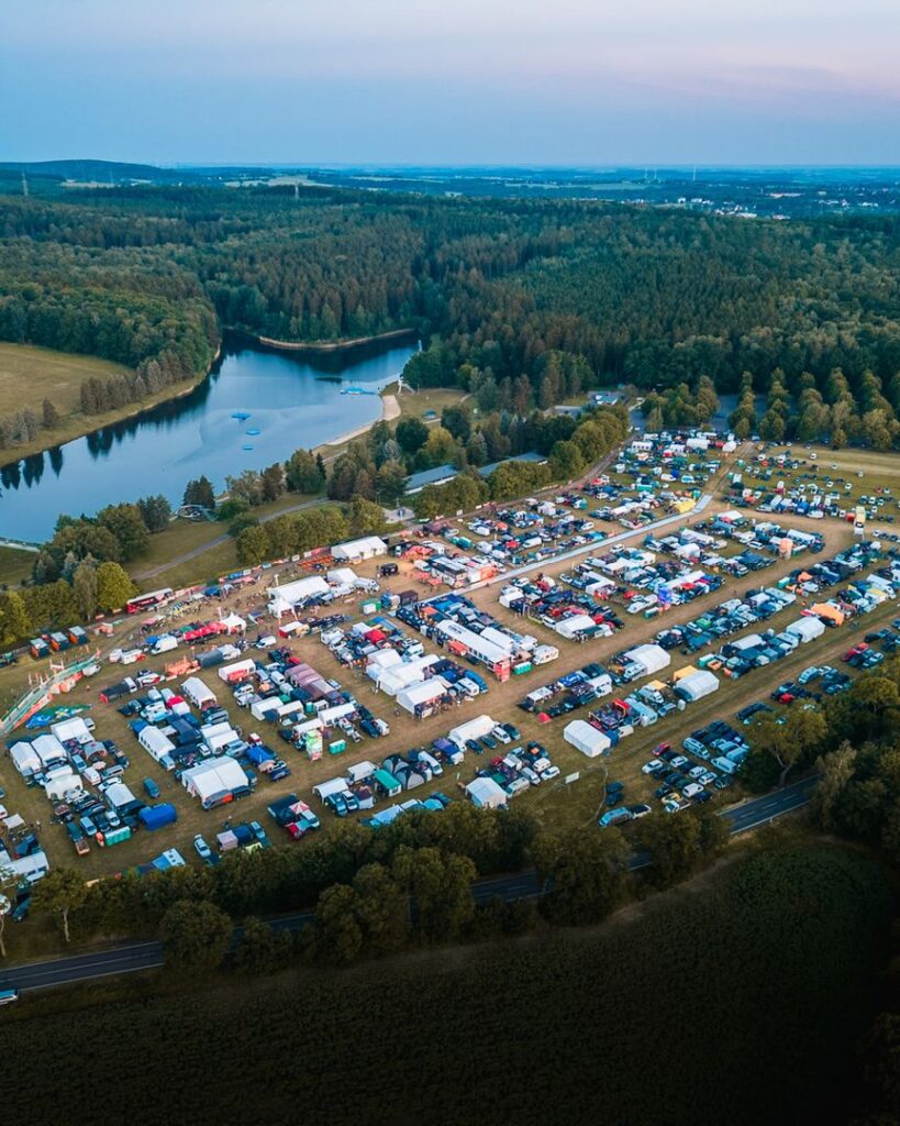 Luftaufnahme vom Heavy24 Eventgelände in Chemnitz mit Fahrerlager, Zelten und einem angrenzenden See
