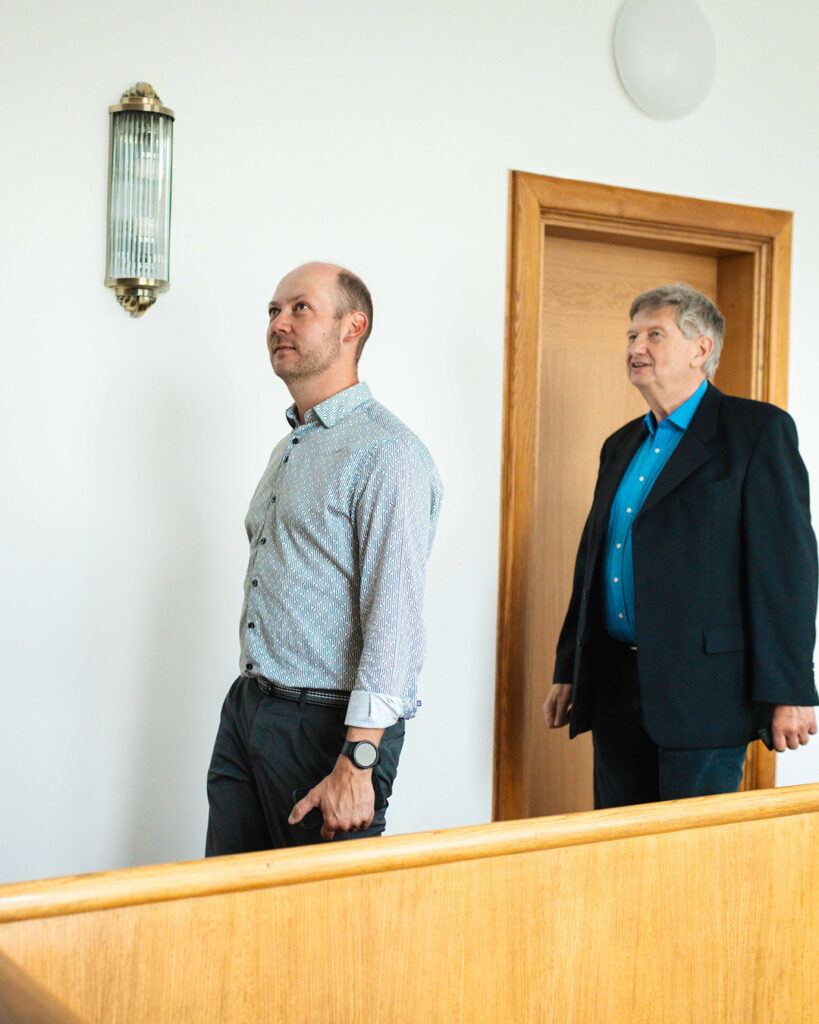 Innenansicht der ROGO-Werke: Ein Mann und der Bürgermeister von Hohenstein-Ernstthal, Lars Kluge, laufen aufmerksam durch den hellen Flur des historischen Gebäudes.