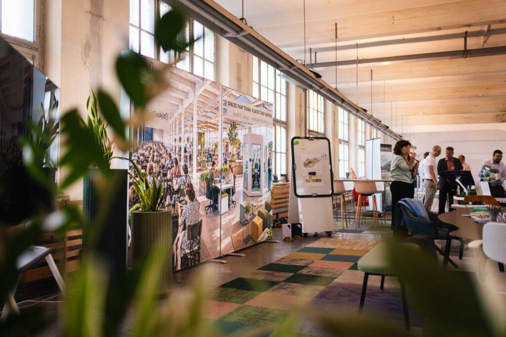 Hell erleuchteter Ausstellungsraum im ROGO Future Campus mit Präsentationswänden und Besuchern.