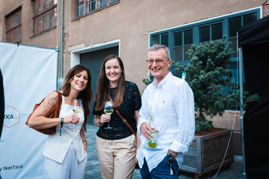 Drei lächelnde Gäste im Gespräch beim Netzwerk-Sommerfest im ROGO-Innenhof.