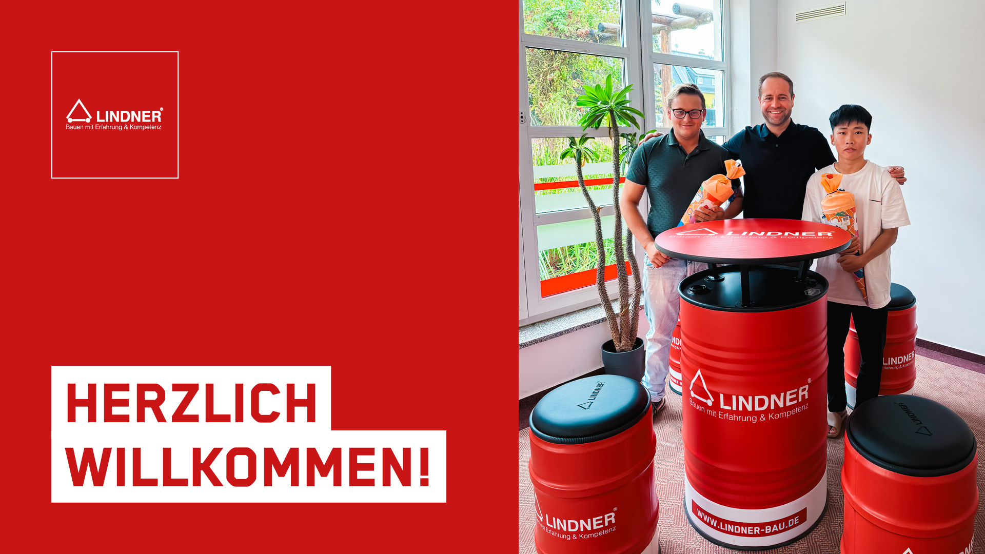 Tony Lindner steht mit zwei neuen Azubis vor roten Stehtischen. Die Azubis halten Zuckertüten in der Hand